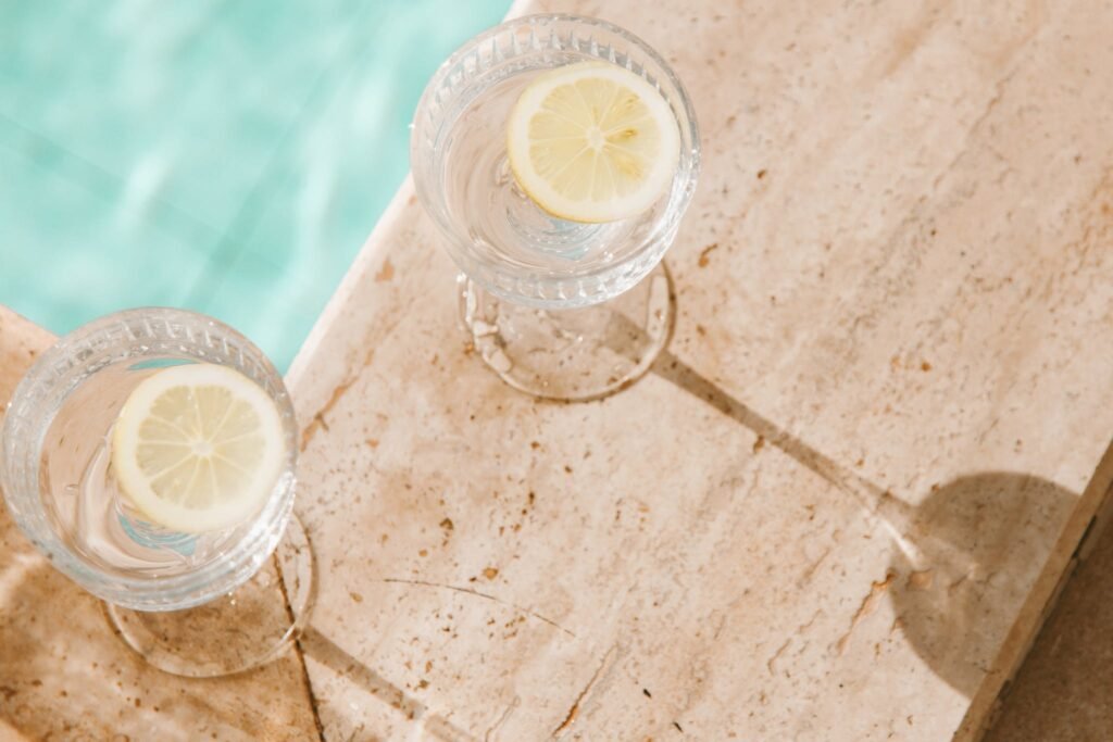 Clear Drinking Glasses With Lemon Slices and Water on a Concrete Surface