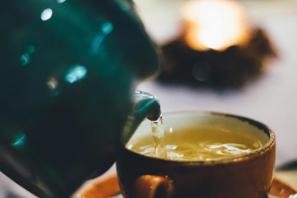 Person Pouring Liquid Into Brown Ceramic Cup