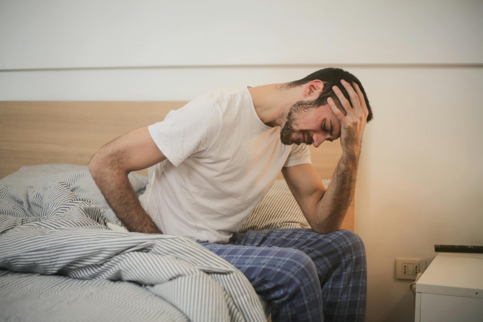 Young man in sleepwear suffering from headache in morning